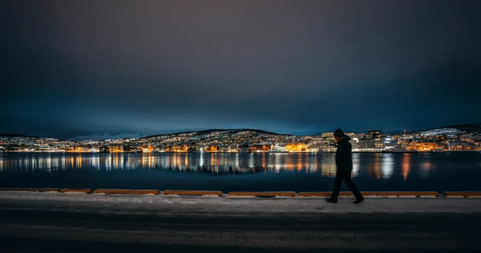 Person går alene langs Tromsø-havna i mørketid — bilde på ensomhet i Norge