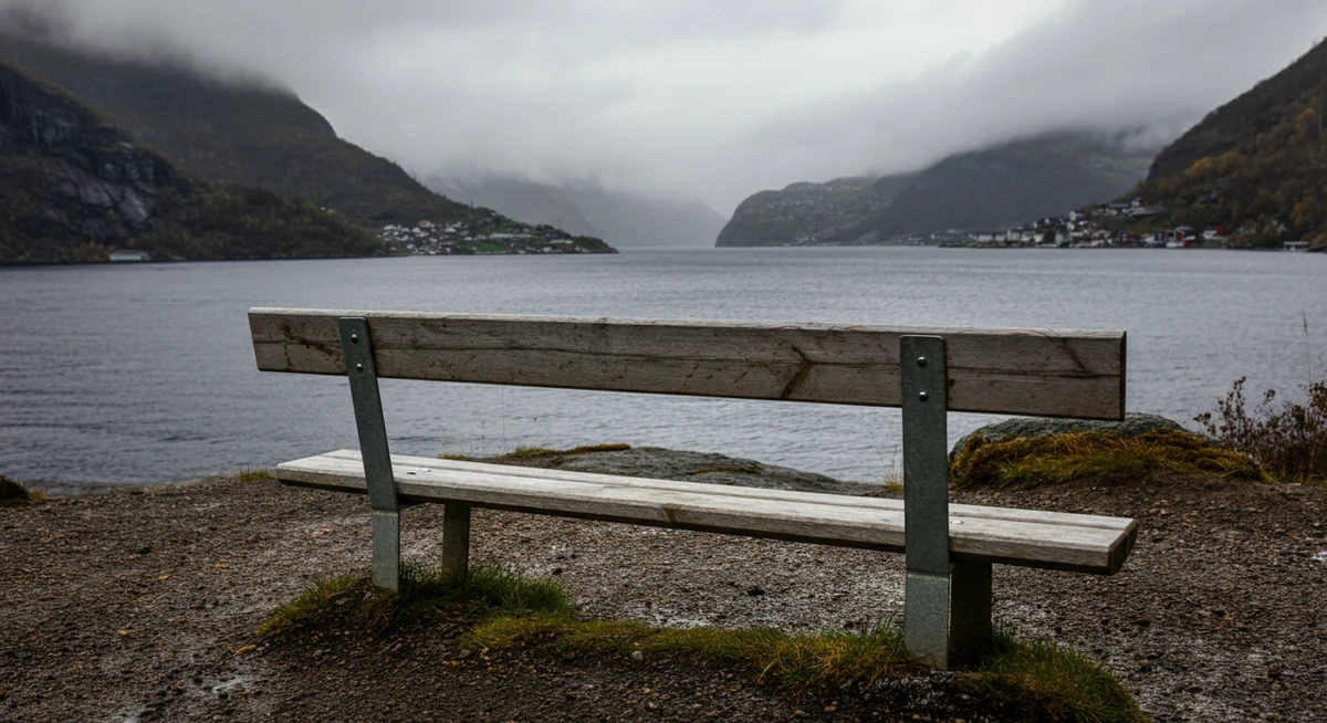 Tom benk ved norsk fjord i overskyet vær — symbol på sosial isolasjon