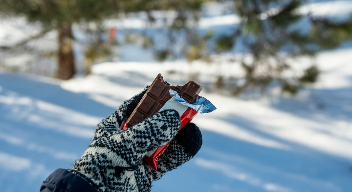Vottekledd hånd med Kvikk Lunsj i påskesola, hyttekiloer som sniker seg på under påske.